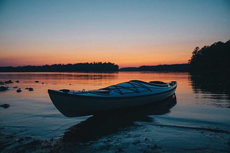 A kayak rests on the shore of a lake in North Carolina, the state where our BCBS drug rehab is located.