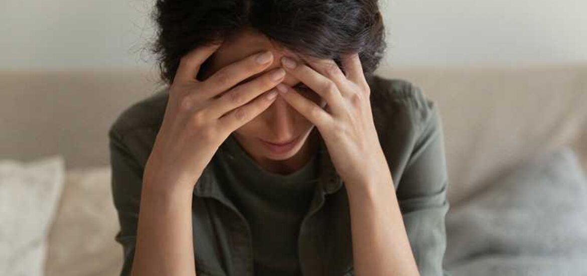 A woman struggling with drug abuse covers her face because she is upset.