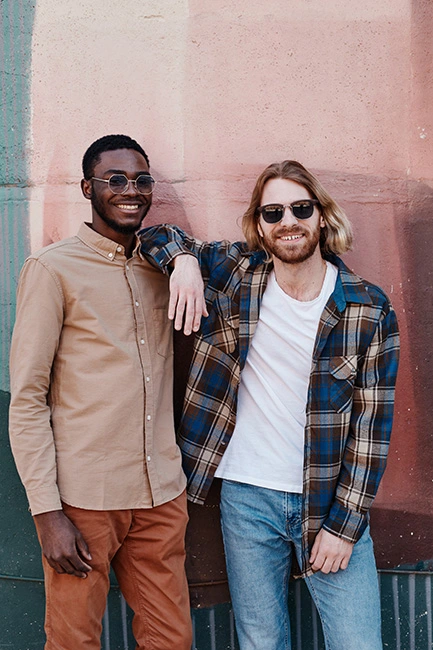 Two friends stand together and smile.