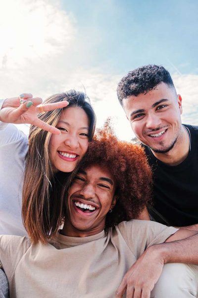 Three friends smile at the camera.